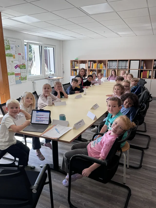 Kinder sitzen bei der ersten Sitzung des Kinderparlaments am Tisch.
