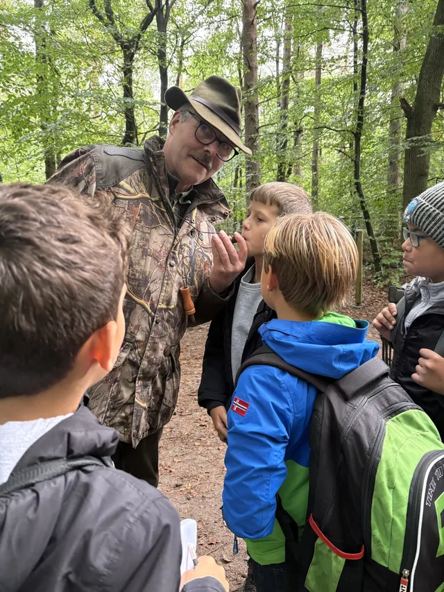 Fachperson erläutert Kindern eine Aufgabe der Waldjugendspiele.