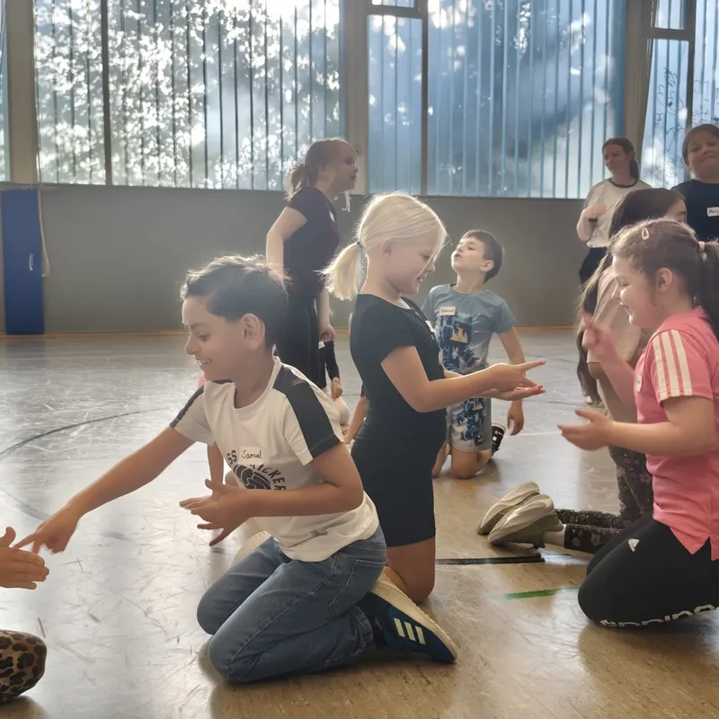 Kinder arbeiten in der Sporthalle bei einer Teambuilding-Übung zusammen.