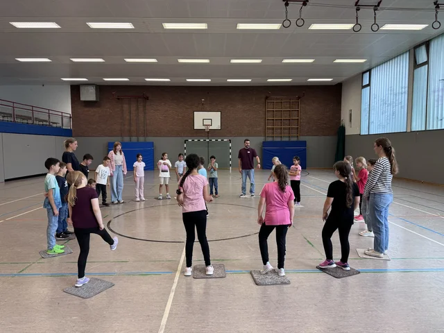 Kinder stehen in einem Kreis bei einer Teambuilding-Übung.