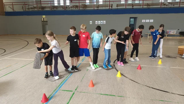 Schülerinnen und Schüler bei einer gemeinsamen Bewegungsaufgabe.