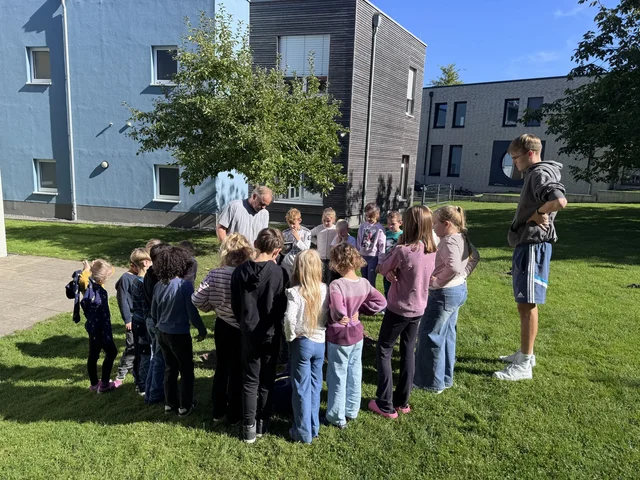Kinder versammeln sich auf der Schulwiese bei der Baumpflanzung.