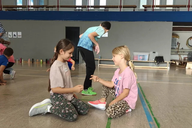Kinder sprechen bei einer Gruppenübung in der Sporthalle miteinander.