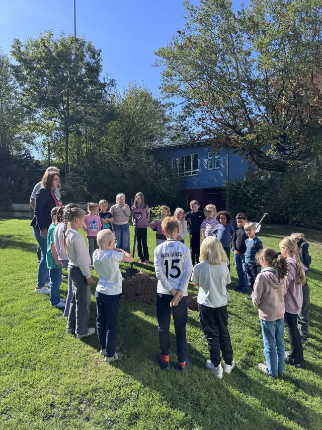 Kinder des Kinderparlaments stehen gemeinsam auf der Schulwiese.